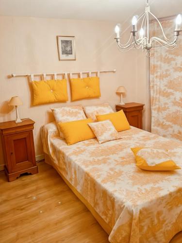 une chambre avec un grand lit avec des oreillers jaunes dans l'établissement Maison de Village au cœur de Laroquebrou, à Laroquebrou