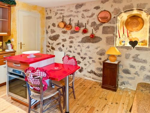 une cuisine avec un comptoir rouge et une table rouge dans l'établissement Maison de Village au cœur de Laroquebrou, à Laroquebrou
