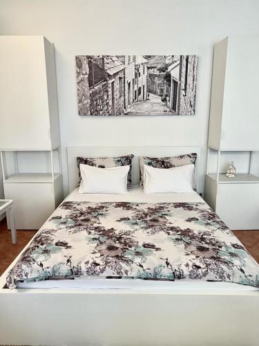 a bedroom with a white bed with a floral bedspread at Pansion Ivana studios in Baška Voda