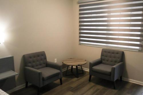 two chairs and a table in a room with a window at Economy Inn Historic District in Saint Augustine