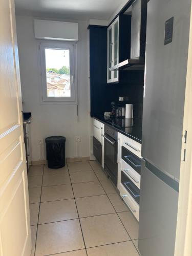 une cuisine avec des appareils en noir et blanc et une fenêtre dans l'établissement Maison a Socoa, à Urrugne