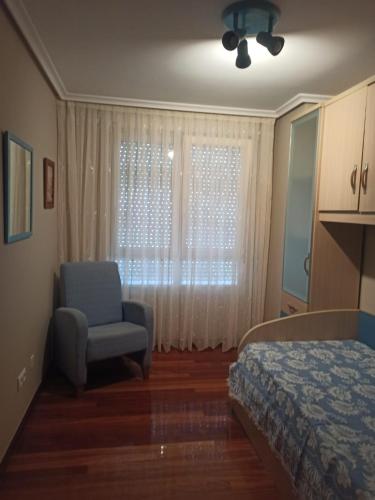 a bedroom with a bed and a chair and a window at Apartamento Casuca, terraza y jardín in Ajo