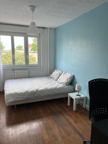 un lit dans une chambre avec un mur bleu dans l'établissement Appartement des merveilles, à Vénissieux