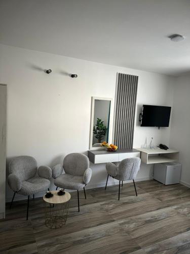 a living room with chairs and a table and a tv at Hotel Mondo in Budva
