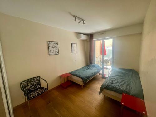 une chambre avec deux lits et une chaise et une fenêtre dans l'établissement Jolie 3 pièces avec terrasse au vieux port, à 2 pas des plages et du palais., à Cannes