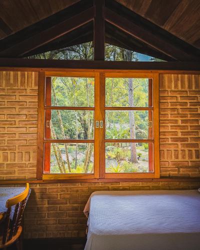 a bedroom with a window in a log cabin at Pousada Conde Redondo in Lumiar