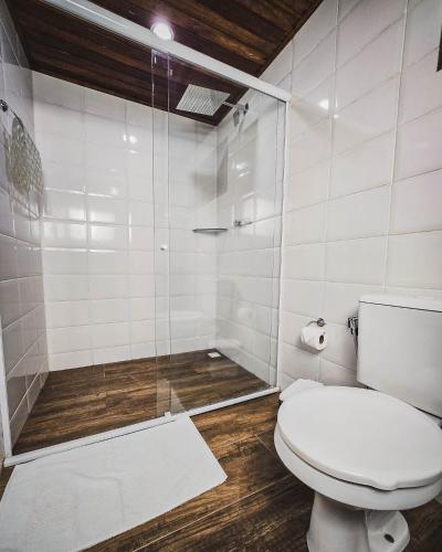 a bathroom with a toilet and a glass shower at Pousada Conde Redondo in Lumiar