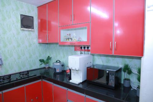 a kitchen with red cabinets and a microwave at Green Dream Homestay 4 Bilik & Ruang Tamu Aircond 3 Bilik Air Wifi Kota Bharu in Kota Bharu