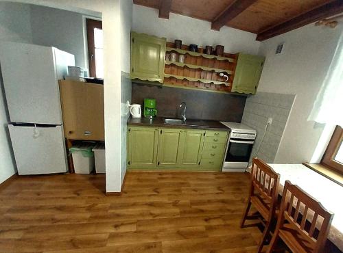 a kitchen with green cabinets and a white refrigerator at Wypoczynek Kocia Góra in Dziemiany