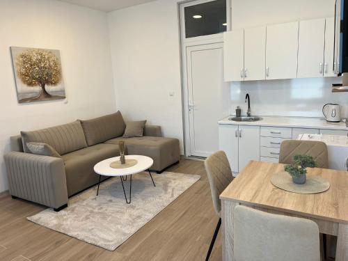 a living room and kitchen with a couch and a table at Apartmani Marić in Gornji Vakuf