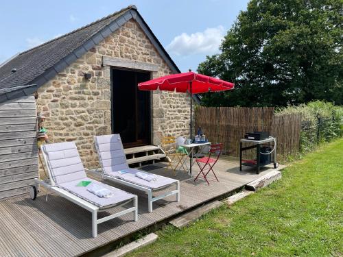 un patio avec deux chaises, une table et un parasol dans l'établissement Gîtes d Izel2 entre terre et mer prés d'un golf, à Ploemel
