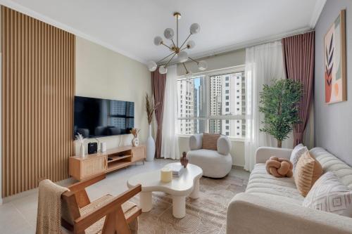 a living room with a couch and a tv at Dubai Marina Promenade 1BR Apartment with Pool near JBR in Dubai