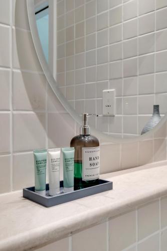 a bathroom counter with a bottle of soap and three cups at Dubai Marina Promenade 1BR Apartment with Pool near JBR in Dubai