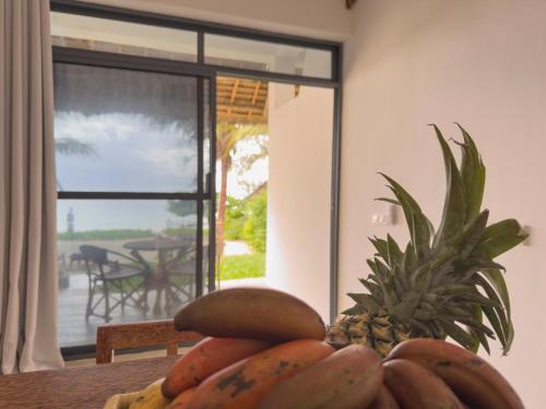 a bowl of fruit on a table with a pineapple at The Coco Paradise in Jambiani