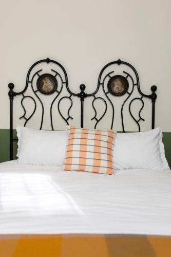 a bed with a black headboard and white pillows at Fritto Misto Comune Stays in Fabriano