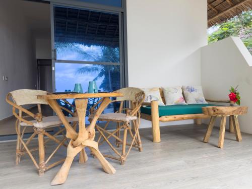 a table and chairs in a room with a couch at The Coco Paradise in Jambiani
