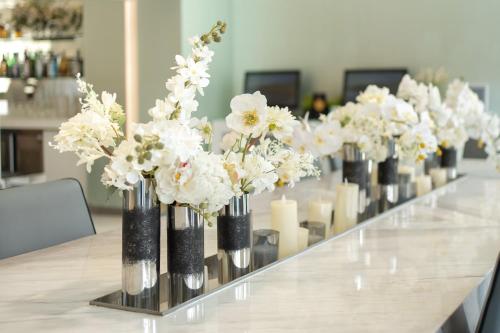 a row of vases filled with white flowers on a table at Ambience Hotel Taipei in Taipei
