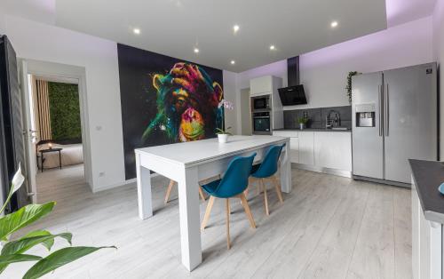 a kitchen with a white table and blue chairs at L'Evolution, 2 suites et jardin in Vesoul