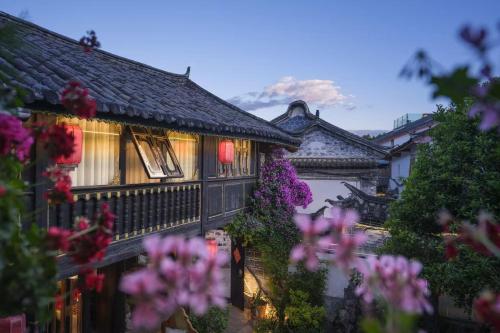 a building with pink flowers in front of it at Yiyuan Snow Mountain View Historical Naxi House - Lijiang Old Town Mufu branch in Lijiang