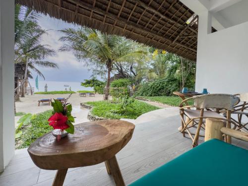 a table with a red flower on it on a patio at The Coco Paradise in Jambiani