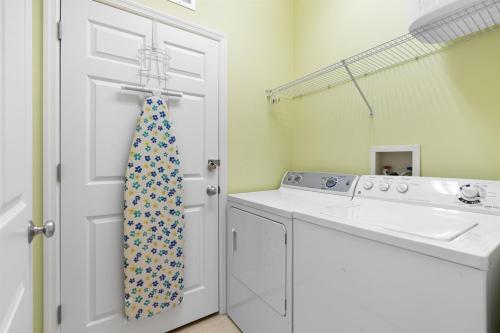 a bathroom with a washing machine and a tie at Stay ON Flagler Avenue! Charming Condo with Full Kitchen, Parking and Courtyard! in Chicken Island