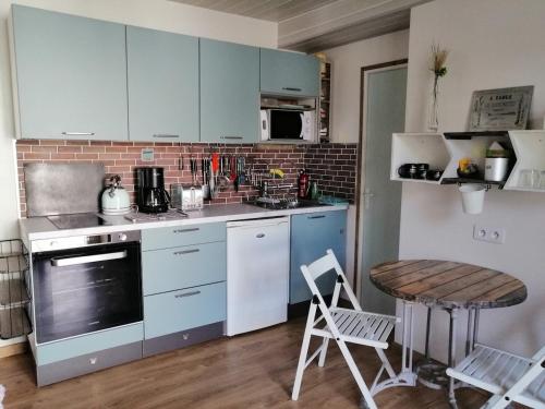 une cuisine avec des armoires bleues et une table et des chaises dans l'établissement Les Lavandes Pornichet, à Pornichet