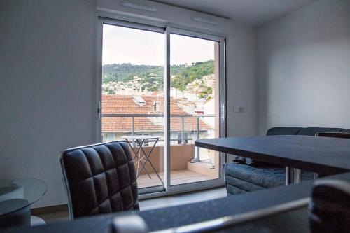 une pièce avec une table et des chaises et une grande fenêtre dans l'établissement Studio climatisé au calme, mezzanine et balcon, à Nice