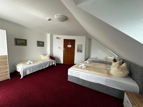 a bedroom with two beds and a red carpet at Polgármester Étterem és Panzió in Fertőszéplak