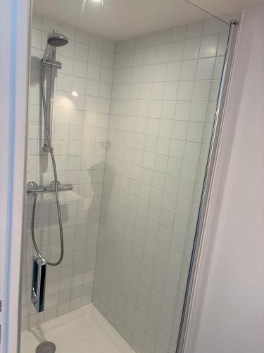 La salle de bains est pourvue d'une douche et de carrelage blanc. dans l'établissement La p’tite maison, à Le Minihic-sur-Rance