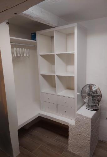 un placard blanc avec des étagères blanches et un ventilateur dans l'établissement Charming studio Haut-de-Cagnes, à Cagnes-sur-Mer