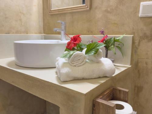 a bathroom sink with flowers on a towel at The Coco Paradise in Jambiani