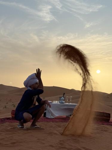 a young boy playing in the sand in the desert at Camel Luxury Camp in Merzouga