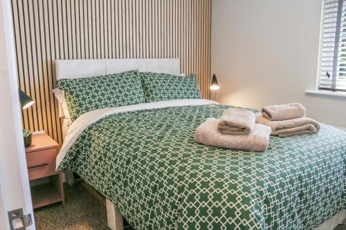 a bedroom with a bed with a green and white comforter at Stylish 2 Bedroom Property in Bury Saint Edmunds