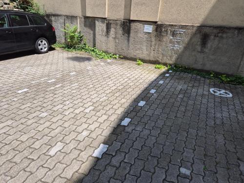 a brick driveway with a car parked next to a building at Central Pécs Bea&Tom in Pécs