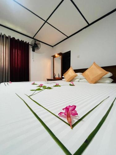 a bedroom with a large white bed with flowers on it at Chaaya Cottage in Bentota