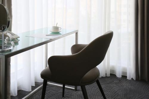 a black chair sitting next to a glass table at Ambience Hotel Taipei in Taipei