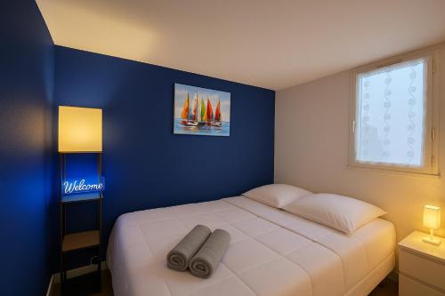une chambre avec un lit blanc avec un mur bleu dans l'établissement Résidence Eureka-clim-parking-Wifi-piscine-Proche village natu, au Cap d'Agde