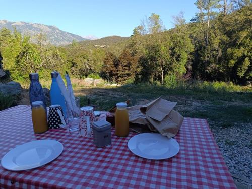 a red and white checkered table with plates and bottles at A Chjusella di E Sertine in Tralonca