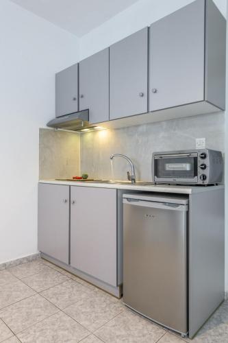 a kitchen with white cabinets and a sink and a microwave at Agnanti View Hotel in Pachaina