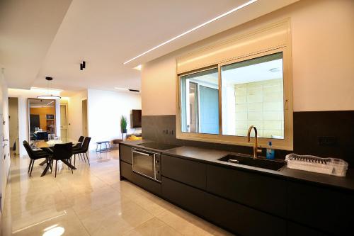 a kitchen with a sink and a table with chairs at אירופה בוטיק כנרת - דירת 4 חדרי שינה עם בריכה ונוף לכנרת in Tiberias