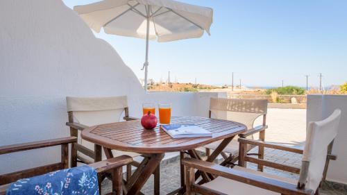 a wooden table with two glasses of orange juice and an umbrella at Agnanti View Hotel in Pachaina