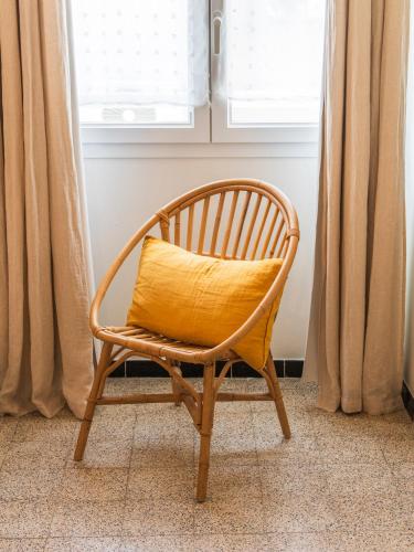 a chair with a yellow pillow sitting in front of a window at Casa Orfea in Algajola