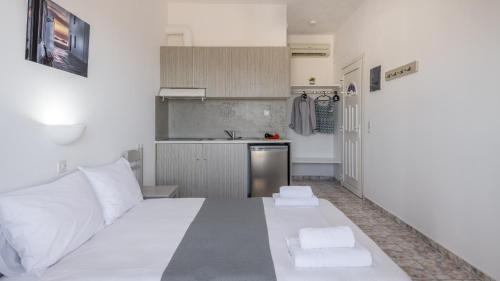 a bedroom with a white bed and a kitchen at Agnanti View Hotel in Pachaina