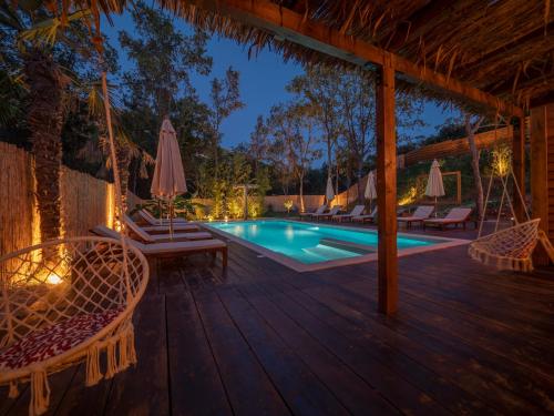 a deck with chairs and a swimming pool at night at Trsteno Beach Apartments in Budva