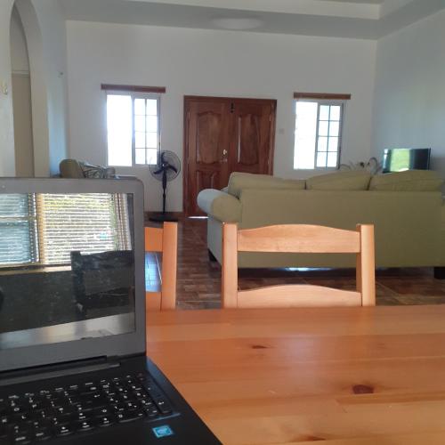 a living room with a laptop computer on a wooden floor at Happy Hall Guesthouse Jamaica in Newmarket