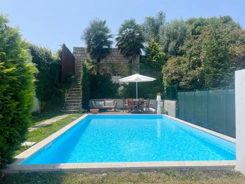 a swimming pool in a yard with an umbrella at Signature Guesthouse 2 in Porto