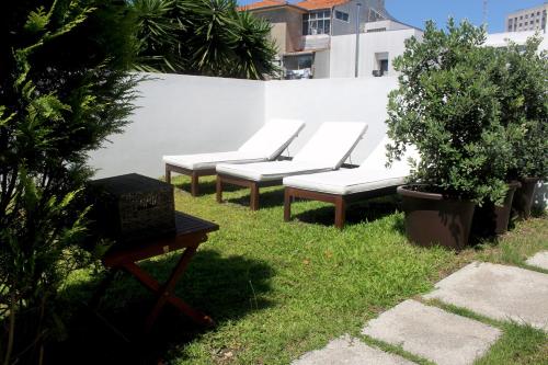 a row of white benches sitting next to a white wall at Signature Guesthouse 2 in Porto