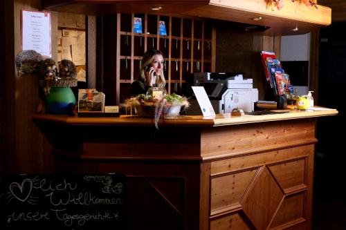 a woman talking on a cell phone behind a counter at Berggasthof Hotel Igelwirt in Schnaittach