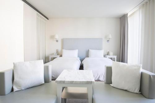 a white hotel room with two beds and a table at Ambience Hotel Taipei in Taipei