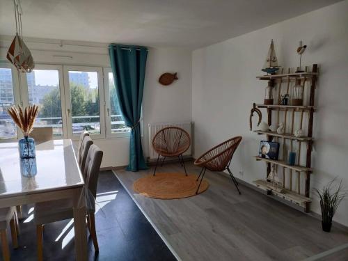 une salle à manger avec une table et des chaises et une fenêtre dans l'établissement Grand appartement L'Hélice - Vue port- 4 Chambres, à Boulogne-sur-Mer